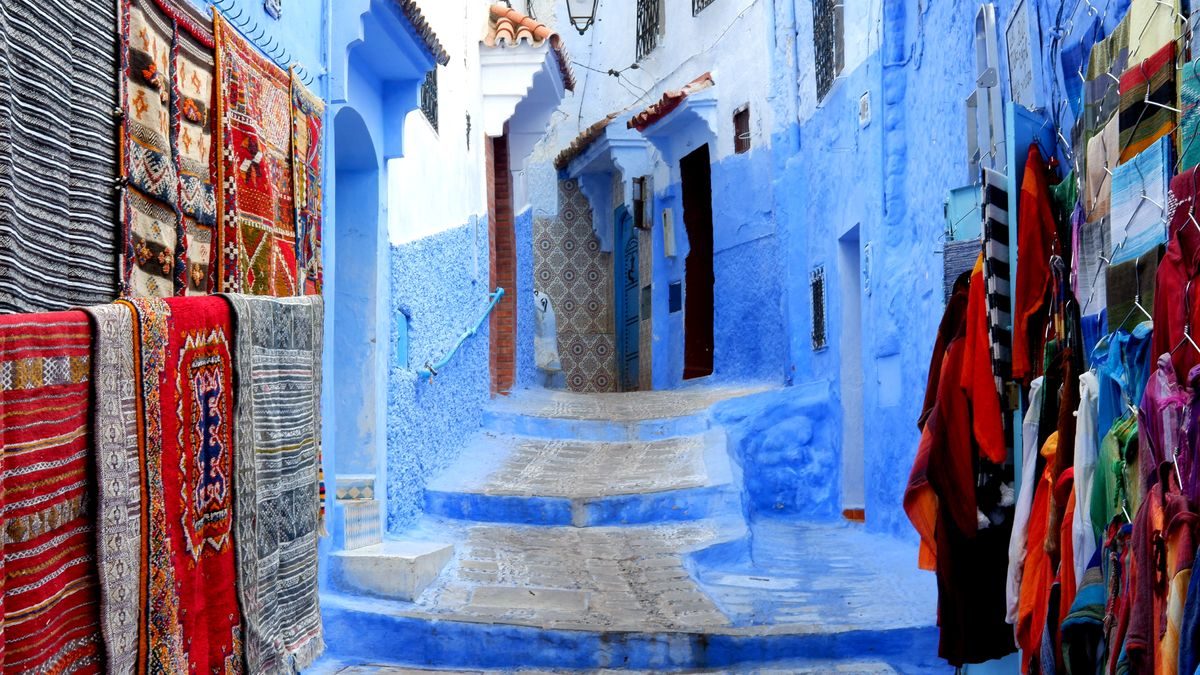 Vicolo blu con tappeti e botteghe di artigianato a Chefchaouen